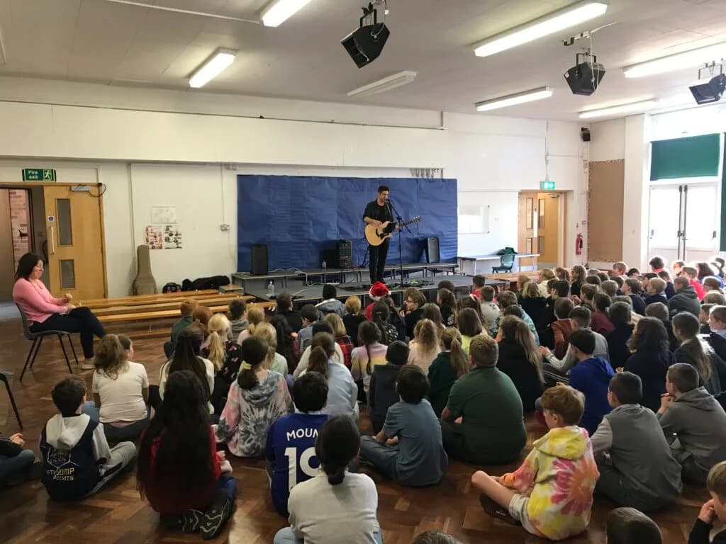 Tutor performing in front of a school assembly