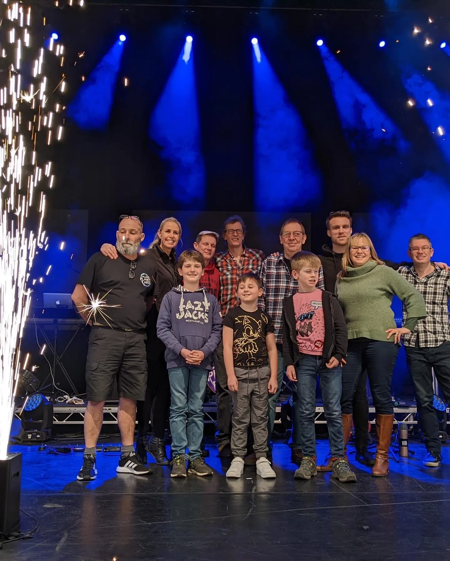Students and parents standing with a professional band on stage before a performance.