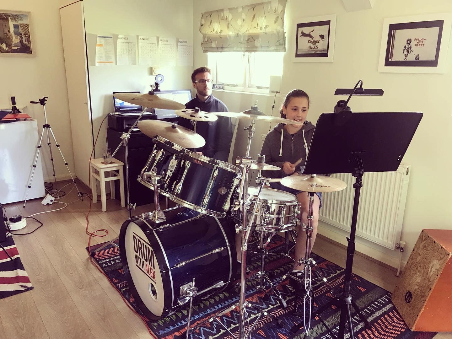 Drum tutor assisting a child with drum practise for kids, fostering a supportive learning environment.