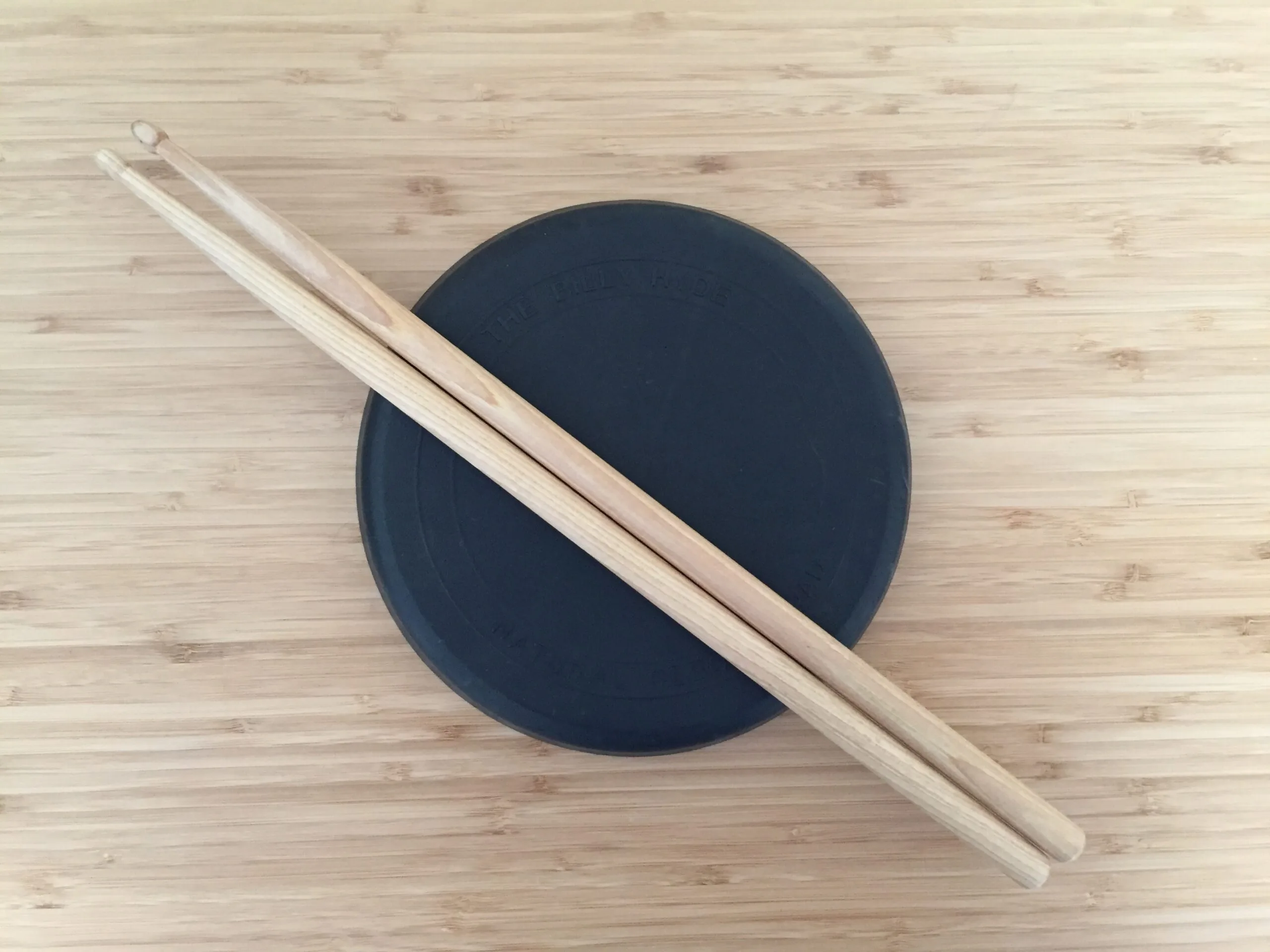 A practice pad with drumsticks on top, essential drum equipment for beginners.