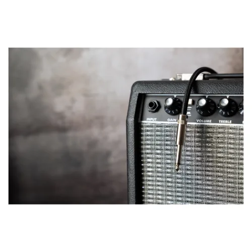 Guitar amplifier and cable as part of a beginner guitar equipment list.