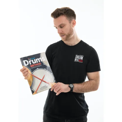 Alex holding the RSL Drums Method book, an excellent resource for beginner drummers.