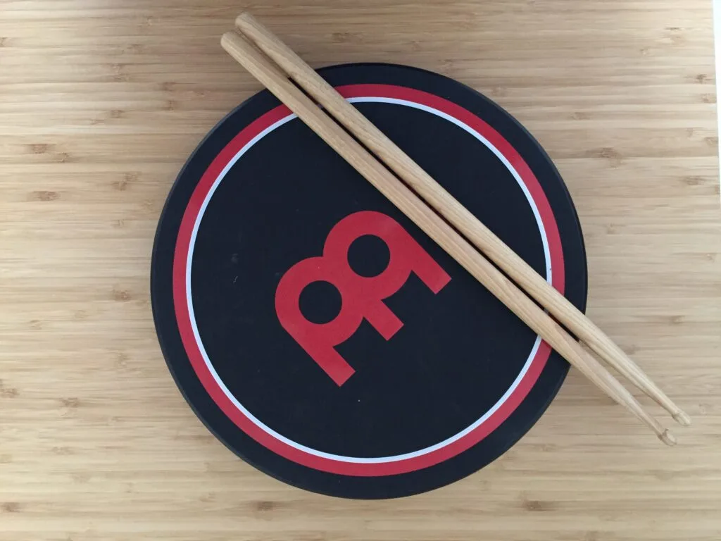A pair of drumsticks resting on a compact practice pad.