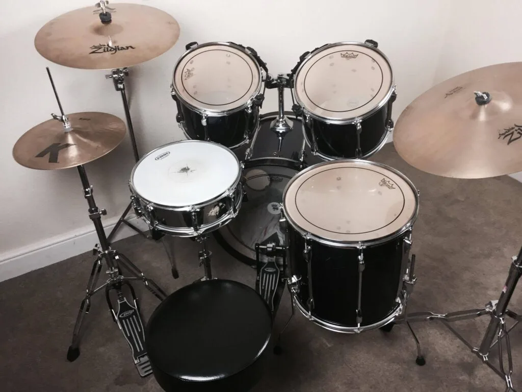 Full acoustic drum kit set up in a home music room with cymbals and drum stool.