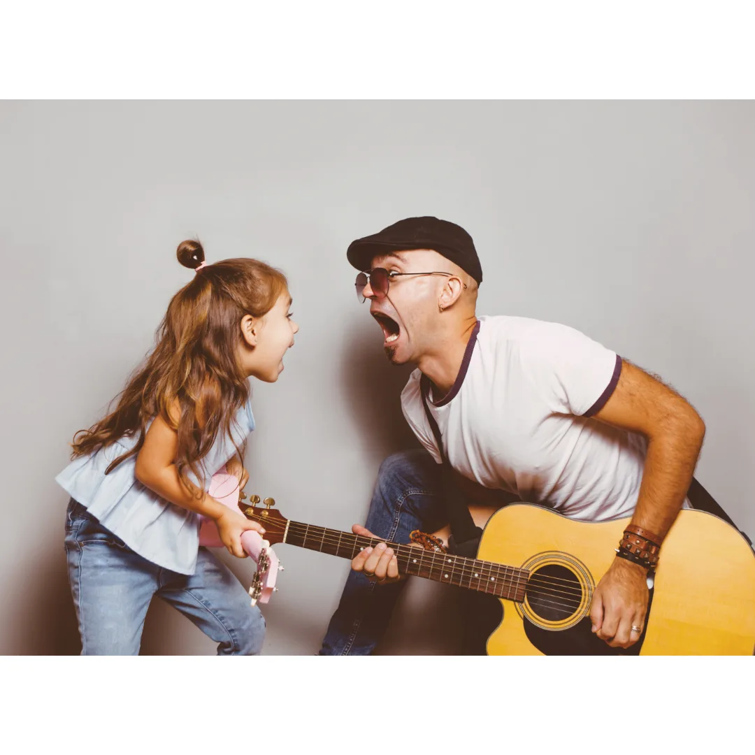 A father and daughter playing guitars together in a professional studio photoshoot, smiling and enjoying the moment.