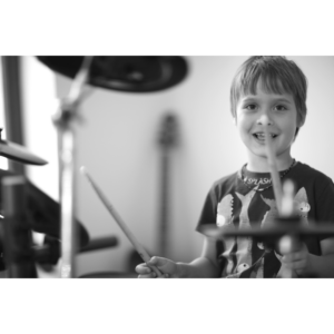 Child practicing drums at home with focused attention.